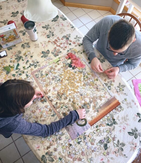 Image shows overhead shot of two people doing a jigsaw together