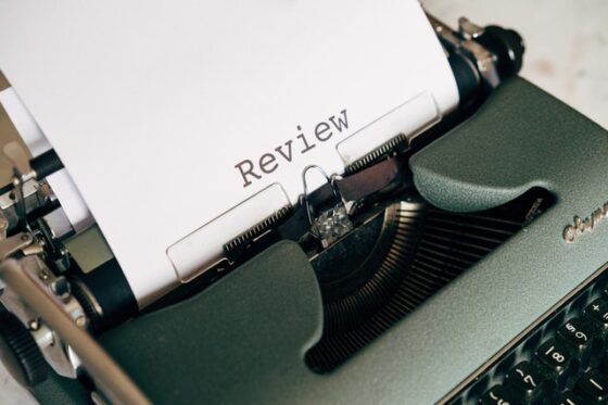 Shows an old school typewriter with the word "review" typed up on a sheet of paper