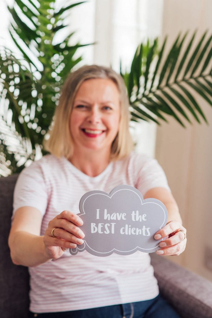 Image shows a woman holding a speech bubble sign in front of her that reads "I have the best clients" | Helen Tarver Freelance Copywriter