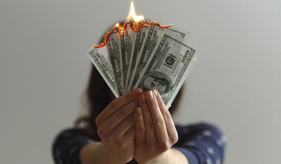 Shows a person holding burning money. Don't squander your stories or it's like burning an asset.