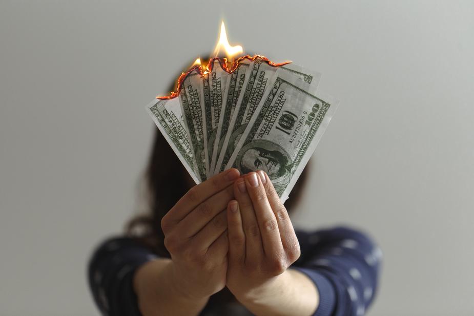 Shows a person holding burning money. Don't squander your stories or it's like burning an asset.