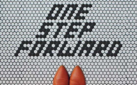 Image shows white and black tiles that say "one step forward" with a part of some red shoes in the bottom of the shot.