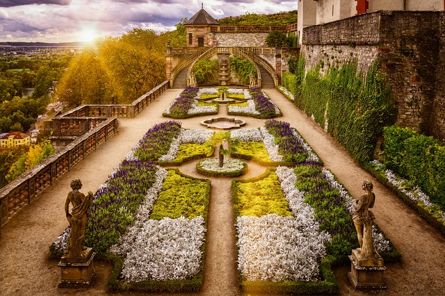 Image shows a formal garden with symmetrical layout of plants in shade of green and grey.