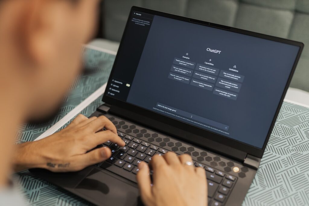 Image shows someone working on a black laptop with the homescreen of ChatGPT open on the screen